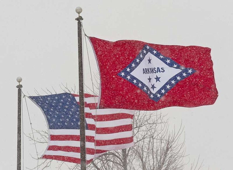 FILE - In this Feb. 1, 2011 file photo, an American and Arkansas flag blow in the wind as snow falls in Fayetteville, Ark.  (AP Photo/Beth Hall, File)