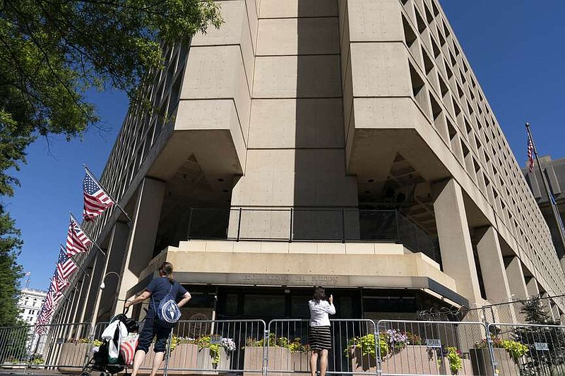 FILE - People take photos of the FBI building headquarters in Washington, Aug. 13, 2022. A federal judge has held veteran investigative reporter Catherine Herridge in civil contempt for refusing to divulge her source for a series of Fox News stories about a Chinese American scientist who was investigated by the FBI but never charged. (AP Photo/Jose Luis Magana, File)