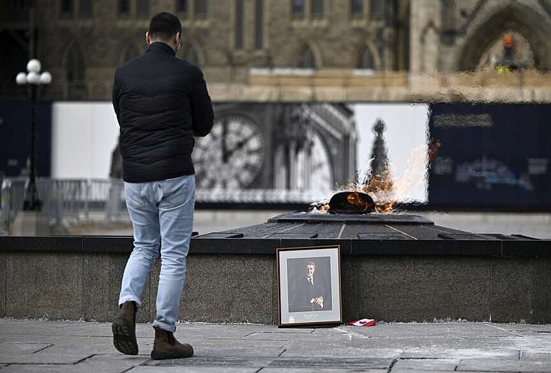 A person looks on at a portrait of former Prime Minister Brian Mulroney that was left by the Centennial Flame on Parliament Hill as Canadians mourn his death at the age of 84, in Ottawa, Canada, on Friday, March 1, 2024. (Justin Tang/The Canadian Press via AP)