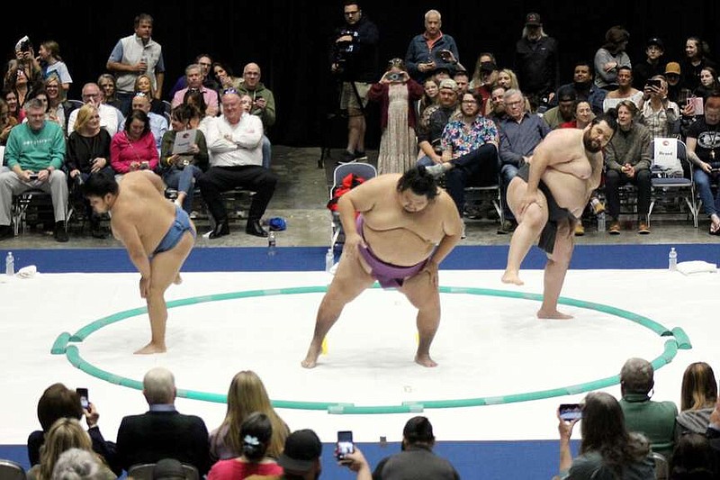 From left, sumo wrestlers Mendee, Hiroki and Ramy perform the shiko, an exercise used to warm up before a match, before Sunday's exhibition at Bank OZK Arena. (The Sentinel-Record/James Leigh)