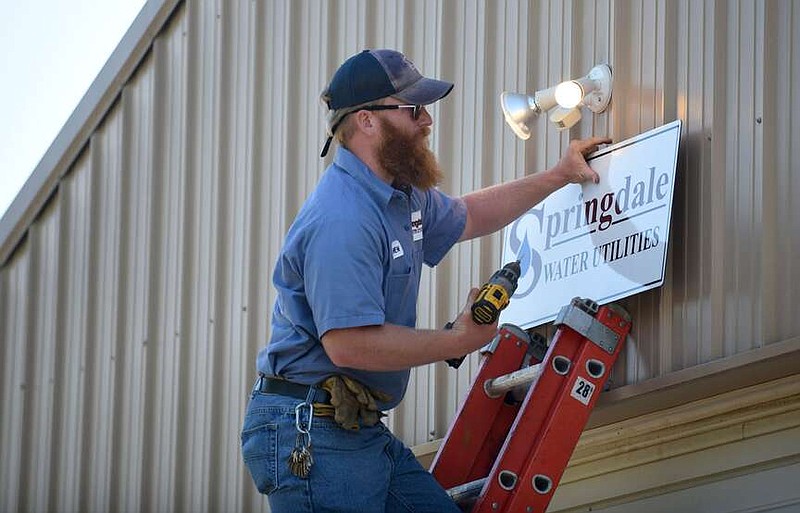 Andrew Brown, a pump station operator, hangs a new sign Aug. 24, 2020, at the former Bethel Heights wastewater treatment facility in Springdale.

(File Photo/NWA Democrat-Gazette)