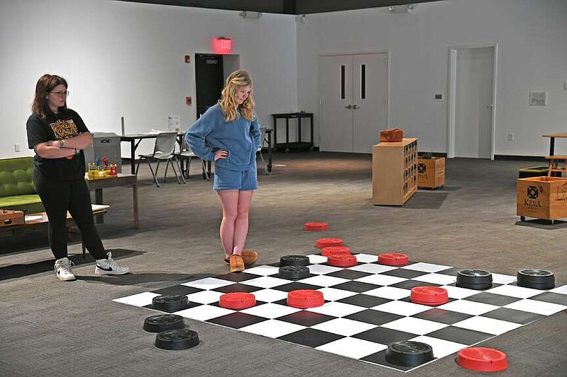 Two girls play a game of checkers on an oversized checkerboard in The Family Room. (The Sentinel-Record/Lance Brownfield)