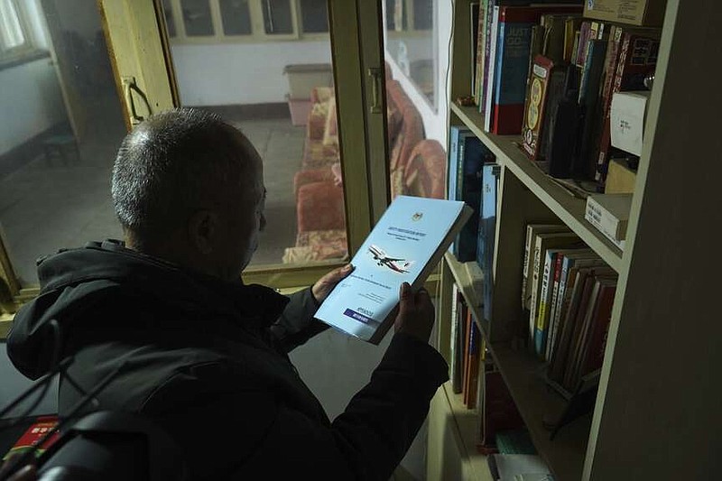 Chinese farmer Li Eryou takes an investigation report on the missing Malaysia Airlines MH370 flight from a bookshelf of his son's former room at a village in Handan in northern China's Hebei province on Feb. 28, 2024. Li, whose son was on the flight, continues to search for answers ten years on. The baffling disappearance of flight MH370 still captivates people around the world. The Boeing 777 left Kuala Lumpur with 239 people on March 8, 2014, but dropped off radar screens shortly after and never made it to Beijing, its destination. Investigators say someone deliberately shut down the plane's communications system and took the plane off course. (AP Photo/Emily Wang Fujiyama)