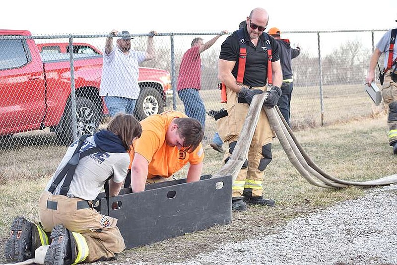 Democrat photo/Garrett Fuller — FILE — California Fire Department volunteers Isaac McDaniel, from left, Kole Ingram and Jay Fortner roll up a hose Feb. 20 after extinguishing a structure fire in the 300 block of Park Street. Rural fire protection districts are struggling to find a sufficient number of volunteers, especially during the day.