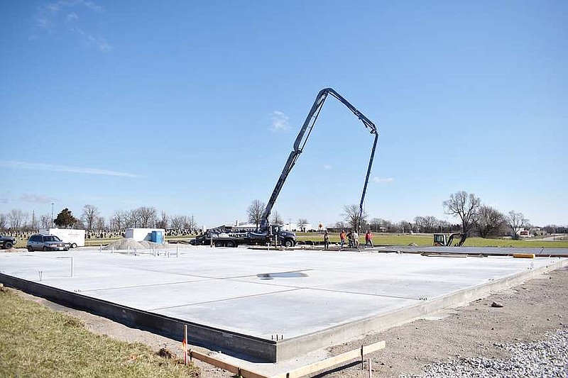 Democrat photo/Garrett Fuller — The boom of a concrete pumping truck is seen March 6, 2024, above a finished portion of the slab foundation for the Moniteau County Sheriff's Office's future home at East Buchanan Street and Windmill Ridge Drive as a crew with Kay Concrete Construction spreads and smooths freshly-poured concrete on a smaller slab on the facility's eastern side.