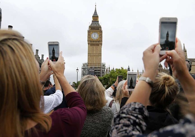 FILE- People record the Big Ben clock at Elizabeth Tower in London, Monday, Aug. 21, 2017. Once again, most Americans will set their clocks forward by one hour this weekend, losing perhaps a bit of sleep but gaining more glorious sunlight in the evenings as the days warm into summer. There's been plenty of debate over the practice but about 70 countries — about 40 percent of those across the globe — currently use what Americans call daylight saving time. (AP Photo/Frank Augstein, File)
