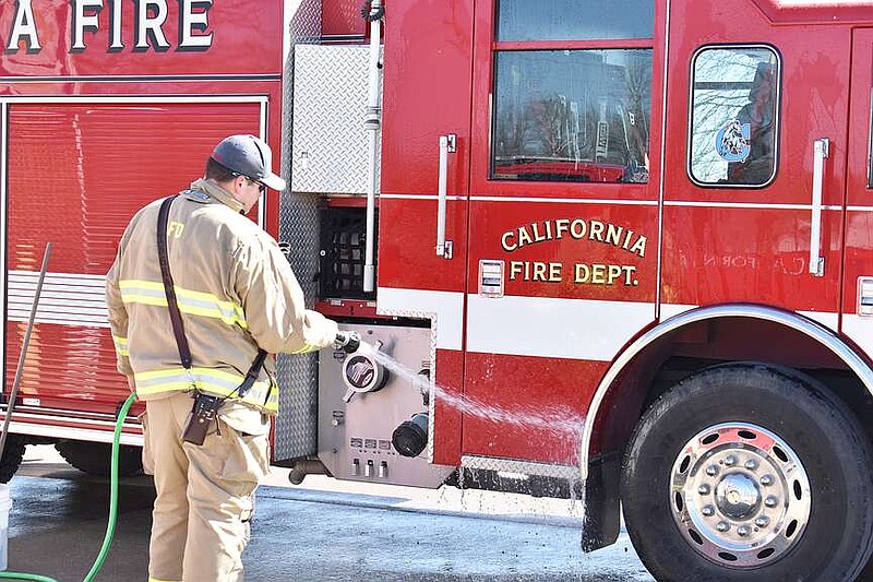 Democrat photo/Garrett Fuller — Monday's mild weather made it a perfect day for outdoor activities, such as making the California Fire Department apparatuses shine like new. Here, volunteer firefighter Kole Ingram sprays remaining soap off a pumper truck Monday in the California Fire Department station driveway.