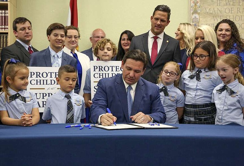 FILE - Florida Gov. Ron DeSantis signs the Parental Rights in Education bill, also known as the "Don't Say Gay" bill, at Classical Preparatory School, March 28, 2022, in Shady Hills, Fla. Students and teachers will be able to speak freely about sexual orientation and gender identity in Florida classrooms, provided it's not part of instruction, under a settlement reached Monday, March 11, 2024, between Florida education officials and civil rights attorneys who had challenged a state law which critics dubbed “Don't Say Gay.” (Douglas R. Clifford/Tampa Bay Times via AP, File)