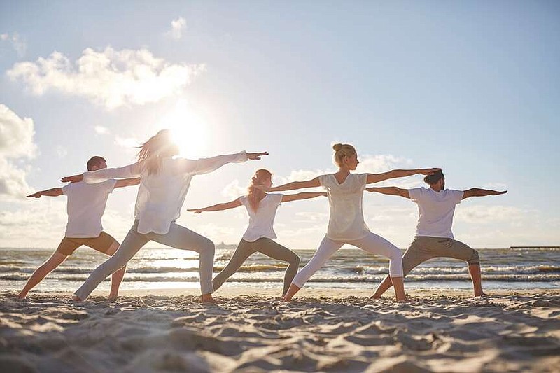 A yoga group makes a warrior pose on a beach. (Submitted photo)