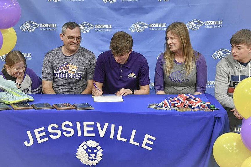 Jessieville High School senior Hunter Pye puts pen to paper on Tuesday at Jessieville Sports Arena to run track at Ouachita Baptist University this fall. (The Sentinel-Record/Lance Brownfield)