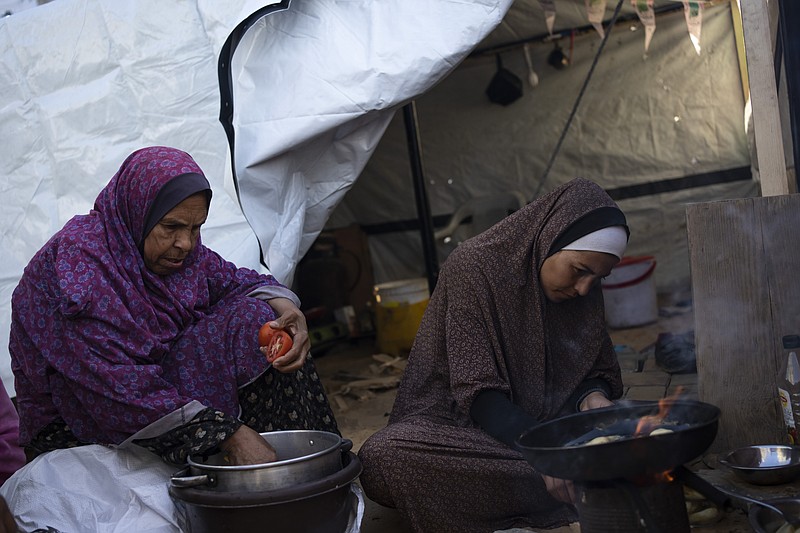 Randa Baker, Right, who was displaced by the Israeli bombardment of the Gaza Strip, prepares the Iftar meal with her mother on the first day of the Muslim holy fasting month of Ramadan at a makeshift tent camp in the Muwasi area, southern Gaza, March 11, 2024. The holy month, typically a time of communal joy and reflection, is overshadowed by the grim reality of a conflict that has claimed over 30,000 Palestinian lives and left vast swaths of Gaza in shambles. (AP Photo/Fatima Shbair)