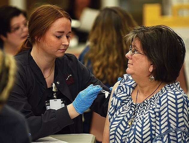 FILE - Briana Halpain (right), a nursing student, administers a flu shot to Linda Martin, a staff member, during the flu shot walk-in clinic in 2022 at the University of Arkansas at Little Rock. (Arkansas Democrat-Gazette/Staci Vandagriff)