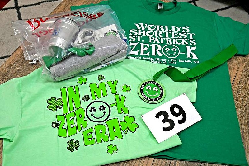 Shirts for the Third Ever Zero-K World's Shortest St. Patrick's footrace are seen along with a medal, race bib and swag bag during packet pickup Thursday. On-site registration for today's race can be done from 2-4 p.m. at the Tri-Lakes CASA tent on Bridge Street. (The Sentinel-Record/Lance Brownfield)