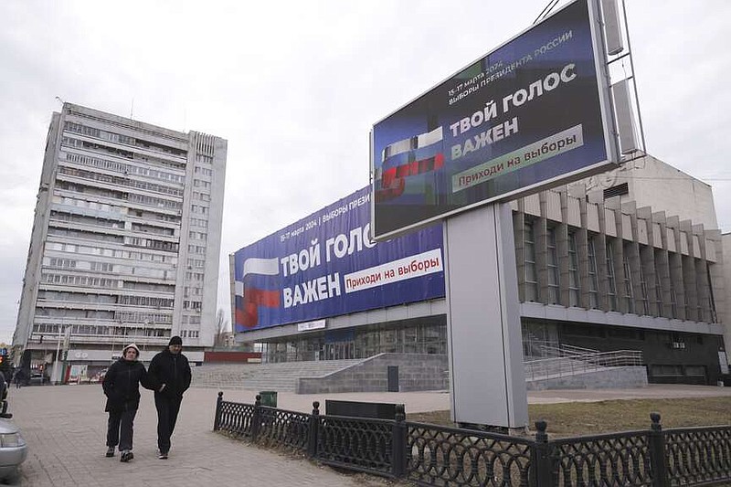 A couple walk past billboards which promote the upcoming presidential election with words in Russian: "Your voice is important" in a street in Luhansk, the capital of Russian-controlled Luhansk region, eastern Ukraine, on Thursday, March 14, 2024. Russian President Vladimir Putin Thursday called on people in Ukraine's occupied regions to vote, telling them and Russians that participation in the elections is "manifestation of patriotic feeling," Presidential elections are scheduled in Russia for March 17. (AP Photo)