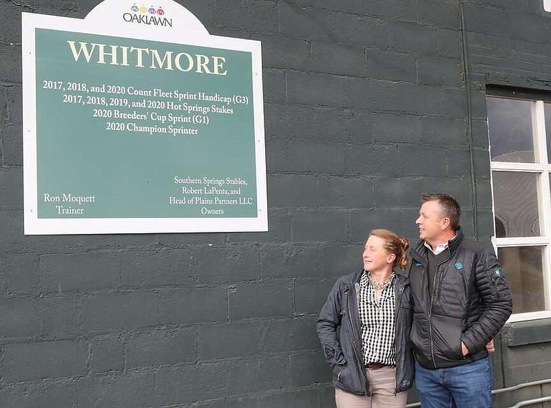 Laura Moquett, left, and her husband Ron Moquett look over the sign at the Whitmore Barn in the stable area at Oaklawn Park, November 12, 2021. (The Sentinel-Record/File photo)