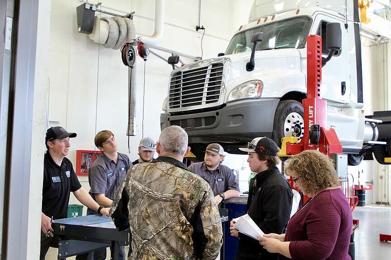 Alexa Pfeiffer/News Tribune photo: 
Denton Daggs, second from right, and his parents visit Saturday, March 16, 2024, with representatives of the Diesel Technology Program at State Technical College of Missouri at the Show Me State Tech event.