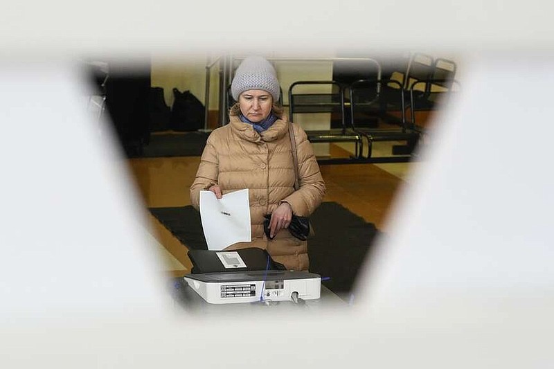 A woman casts a ballot at a polling station during a presidential election in St. Petersburg, Russia, Saturday, March 16, 2024. Voters in Russia are heading to the polls for a presidential election that is all but certain to extend President Vladimir Putin's rule after he clamped down on dissent. (AP Photo/Dmitri Lovetsky)