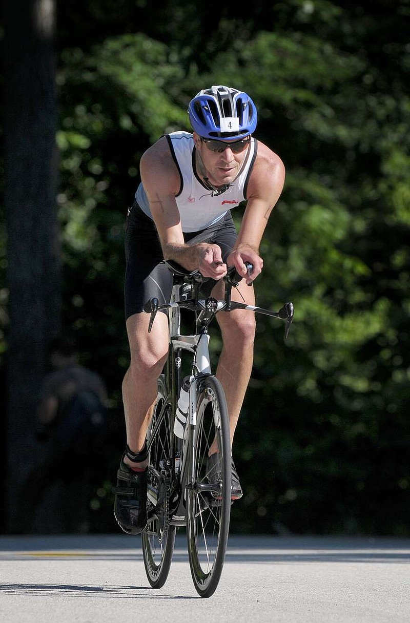 Nathan Kuntz of Broken Arrow, Okla., competes June 5, 2016, in the cycling stage during the Ozark Valley Triathlon at Lake Wedington Recreation Area near Fayetteville. The U.S. Forest Service has allowed the event to continue the past few years even though the area is closed for other types of activities.
(File Photo/NWA Democrat-Gazette)