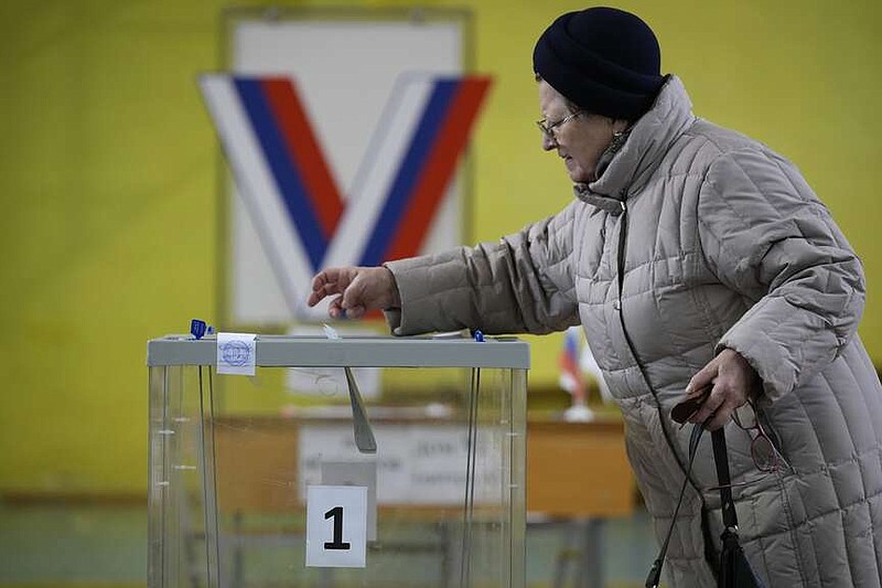 A woman casts a ballot at a polling station located in the school gymnasium during a presidential election in St. Petersburg, Russia, Friday, March 15, 2024. Voters in Russia are heading to the polls for a presidential election that is all but certain to extend President Vladimir Putin's rule after he clamped down on dissent. (AP Photo/Dmitri Lovetsky)