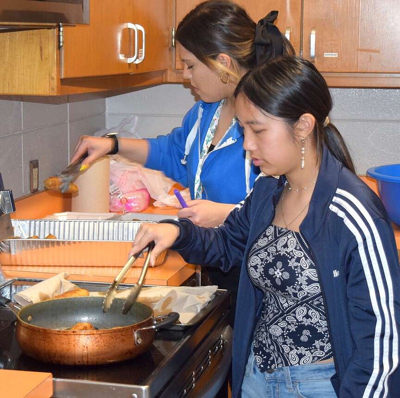 Mike Eckels/Special to the Eagle Observer
McKinzie Thao (right) fries up a fresh batch of egg rolls as Kate Herrera packages them for distribution during the junior class egg roll fundraiser at Decatur High School on March 13.