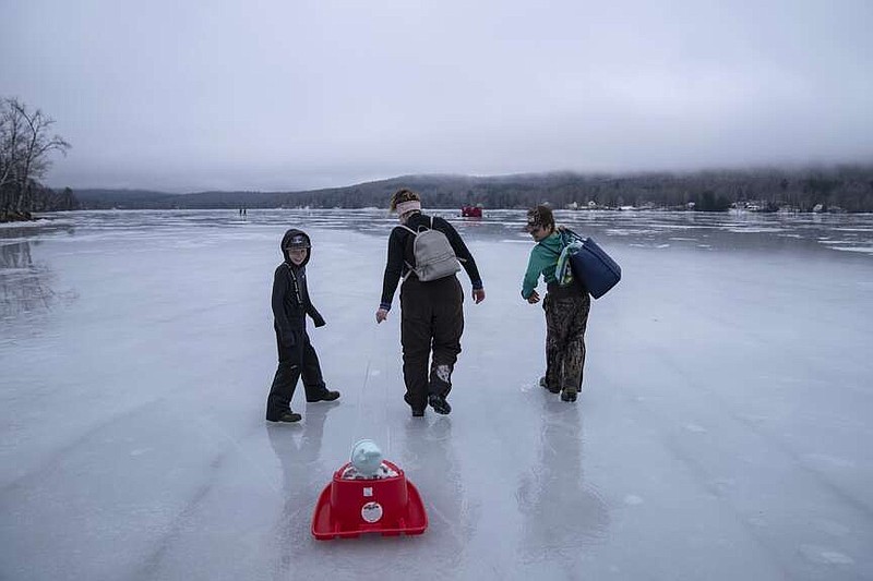 Deija Burbank, center, pulls her six-month-old daughter, Freya, in a sled while ice fishing with her sons, Emmett, 11, left, and Dylan, 12, on a frozen Lake Elmore, Sunday, March 3, 2024, in Elmore, Vt. (AP Photo/David Goldman)