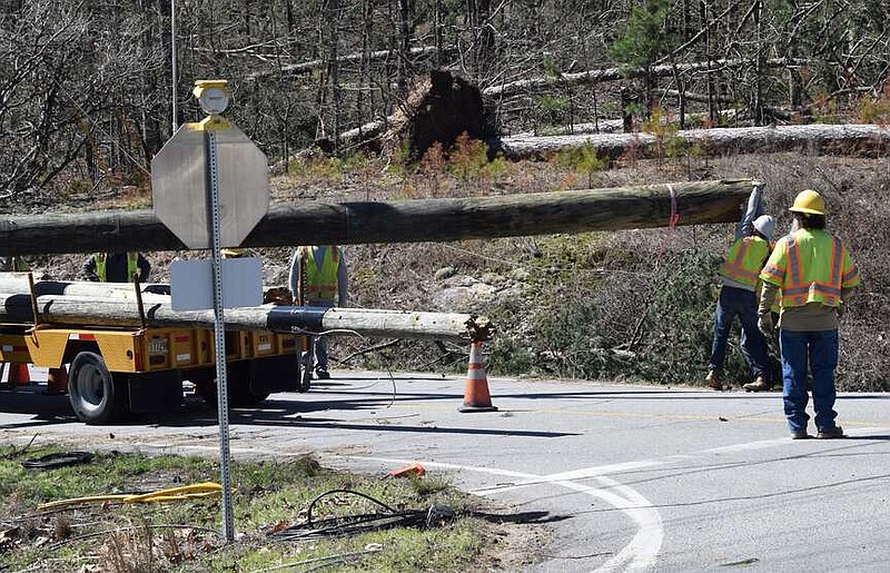 A crew works to load a broken power pole onto a trailer Monday. An EF2 tornado hit Hot Springs Village and the surrounding area on March 14, leaving a path of damage 1,000 yards wide and nearly 8.5 miles long. (The Sentinel-Record/Donald Cross)
