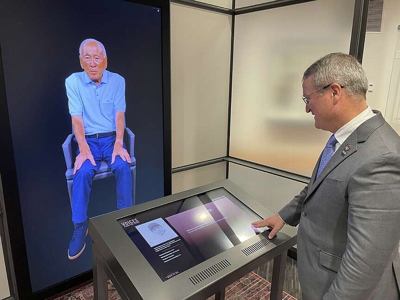 Peter Crean of the National WWII Museum in New Orleans stands at an interactive exhibit with an image of Japanese-American WWII veteran Lawson Ichiro Sakai, who served in the U.S. Army, Tuesday, March 19, 2024. Sakai and 17 other people, including World War II combat veterans, a military nurse, an aircraft factory worker and a USO performer, made extensive video-recordings about their lives and service as part of an interactive exhibit opening at the museum March 20. (AP Photo/Kevin McGill)