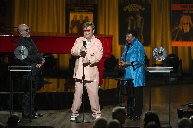 Elton John shares a laugh with Bernie Taupin, left, and Librarian of Congress Carla Hayden, right, during the 2024 Library of Congress Gershwin Prize for Popular Song tribute concert honoring John and Taupin at DAR Constitution Hall on Wednesday, March 20, 2024, in Washington. (AP Photo/Kevin Wolf)