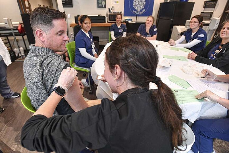 Shane Jennings, a parent of a Future School of Fort Smith student, receives a flu shot from University of Arkansas-Fort Smith nursing student Bethany Willmann, Tuesday, Oct. 25, 2022, at a free community flu clinic hosted by the Arkansas Department of Health's Sebastian County Health Unit inside the Future School's teacher lounge in Fort Smith. (NWA Democrat-Gazette/Hank Layton)