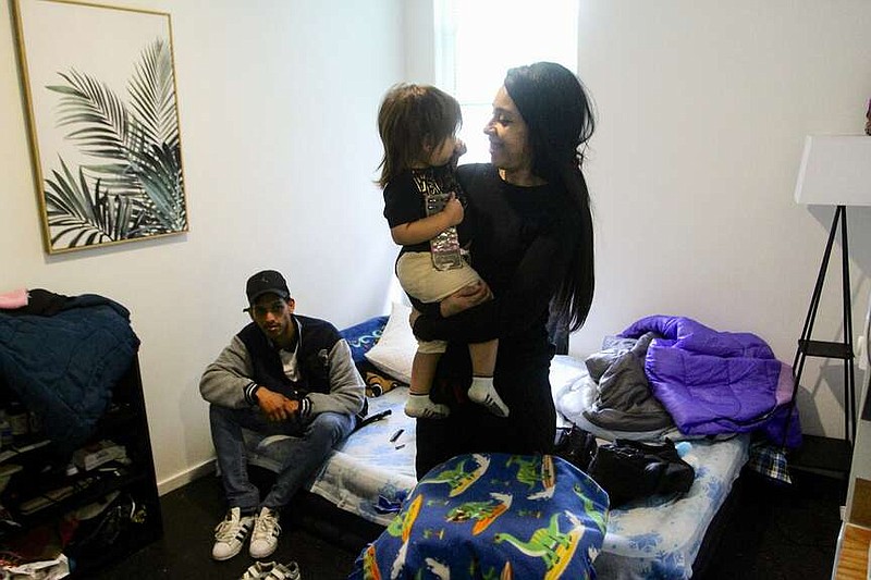 Barbara Peraza-Garcia holds her 2-year-old daughter, Frailys, while her partner Franklin Peraza sits on their bed in their 'micro apartment' in Seattle on Monday, March 11, 2024. (AP Photo/Manuel Valdes)