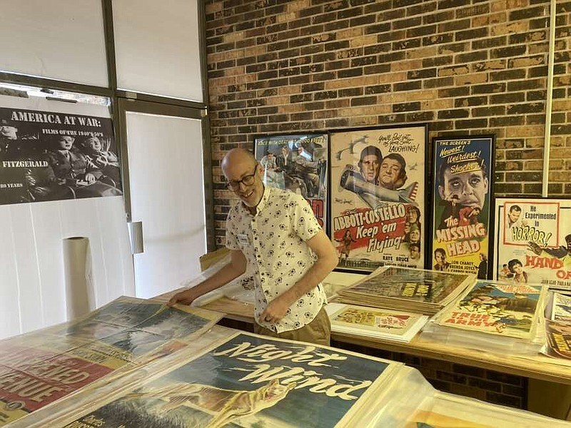 Curator Darren Riley with some of the Michael G. Fitzgerald's extensive collection of movie posters. “Night Wind” is a 1948 spy thriller that stars Michael Ftitzgerald's pen pal Gary Gray.  (Arkansas Democrat-Gazette/Philip Martin)