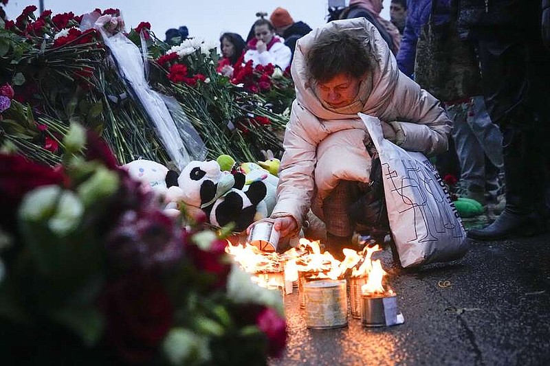A woman lights candles at the fence next to the Crocus City Hall, on the western edge of Moscow, Russia, Saturday, March 23, 2024. Russia's top state investigative agency says the death toll in the Moscow concert hall attack has risen to over 133. The attack Friday on Crocus City Hall, a sprawling mall and concert venue on Moscow's western edge, also left many wounded and left the building a smoldering ruin. (AP Photo/Alexander Zemlianichenko)