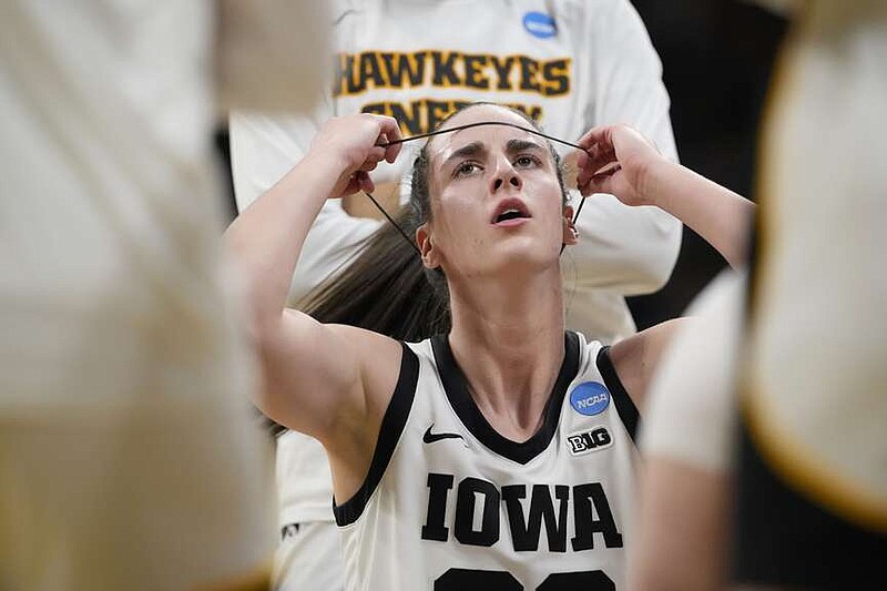 Iowa guard Caitlin Clark (22) adjusts a headband during a timeout in the first half of a first-round college basketball game against Holy Cross in the NCAA Tournament, Saturday, March 23, 2024, in Iowa City, Iowa. (AP Photo/Matthew Putney)