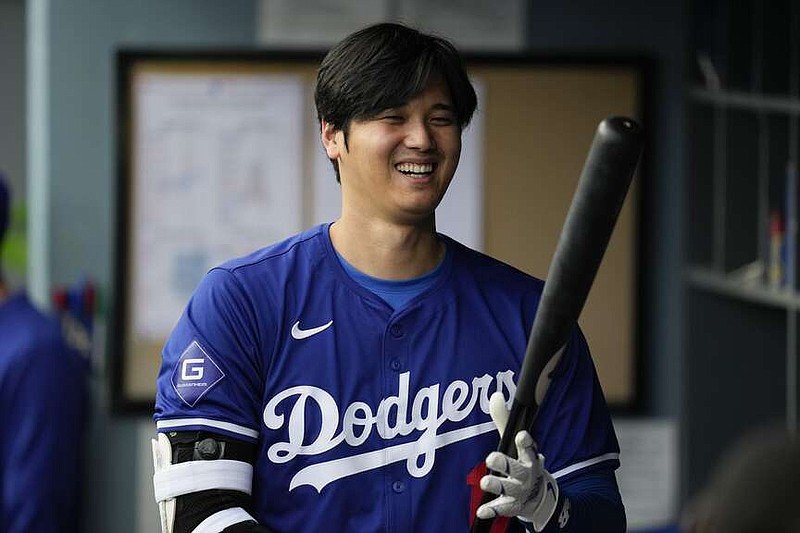 Los Angeles Dodgers designated hitter Shohei Ohtani (17) prepares his bat in the dugout during the first inning of a spring training baseball game against the Los Angeles Angels in Los Angeles, Sunday, March 24, 2024. (AP Photo/Ashley Landis)
