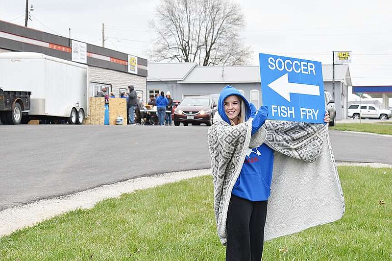Democrat photo/Garrett Fuller — California High School freshman Allison Hackett, co-captain of the Lady Pintos soccer team, holds a sign March 22 urging motorists on West Buchanan Street to stop by the Lady Pintos Soccer Booster Club's fish fry fundraiser in the Ace Realty parking lot. Although the team's inaugural season just began, it is already fundraising for the 2025 season. The program must be financially self-sufficient for its first three seasons, and play as a travel team for the first two.