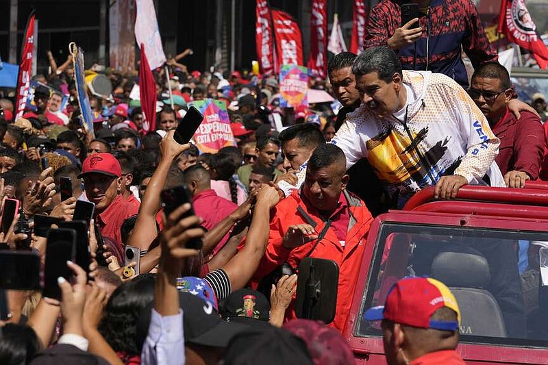 Venezuelan President Nicolas Maduro greets supporters as he is driven to the National Election Commission (CNE) to formalize his candidacy to run again for president in Caracas, Venezuela, Monday, March 25, 2024. Elections are set for July 28. (AP Photo/Matias Delacroix)