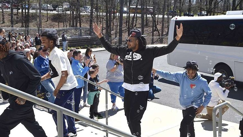 The Nighthawks' Nakavieon White, center, raises his arms in celebration as members of the team make their way up the steps of the National Park College Student Commons Tuesday during a ceremony honoring the newly-crowned NJCAA national champions. (The Sentinel-Record/Donald Cross)