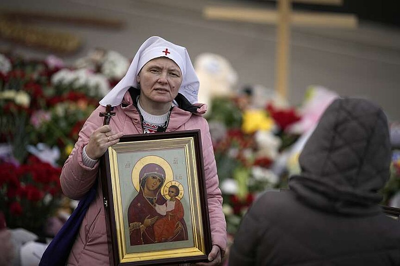 An Orthodox believer attends a service at a makeshift memorial in front of the Crocus City Hall on the western outskirts of Moscow, Russia, Tuesday, March 26, 2024. Russian state news agency Tass says 22 victims of the concert hall attack that killed more than 130 people remain in serious condition in the hospital. (AP Photo/Alexander Zemlianichenko)