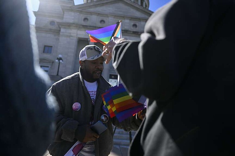 Keon Anderson, from the Be YoUUU Organization, hands out lgbtq flags at the start of a demonstration on the steps of the Arkansas State Capitol on Tuesday, March 26, 2024 protesting the recent emergency order removing X gender designations from Arkansas drivers licenses. More photos at arkansasonline.com/327protest/

(Arkansas Democrat-Gazette/Stephen Swofford)
