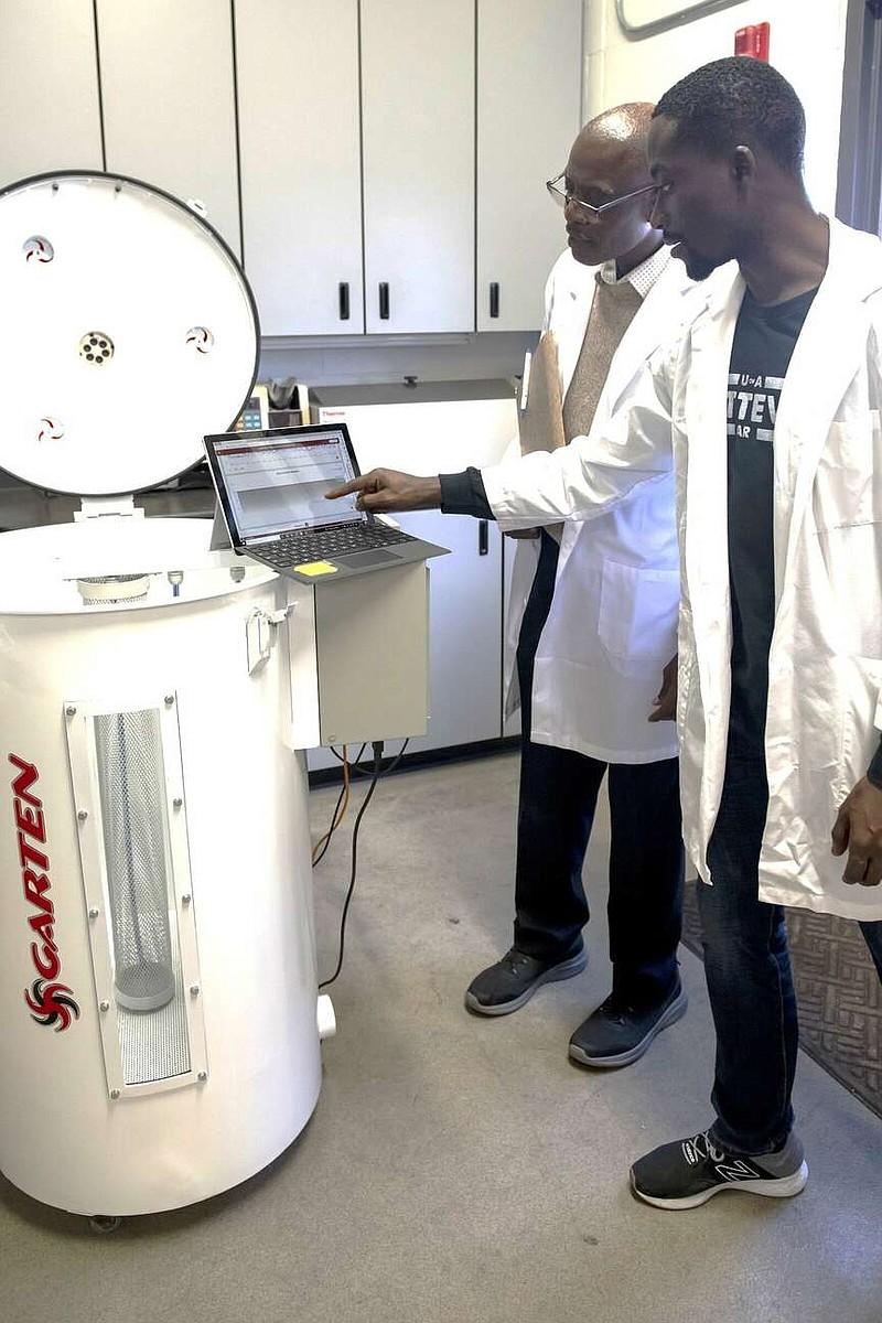 Griffiths Atungulu  (left) director of the Rice Processing Program, works with Samuel Olaoni, Ph.D. student, on a miniature grain bin to test carbon dioxide sensors for monitoring grain quality. (Special to The Commercial/University of Arkansas System Division of Agriculture)