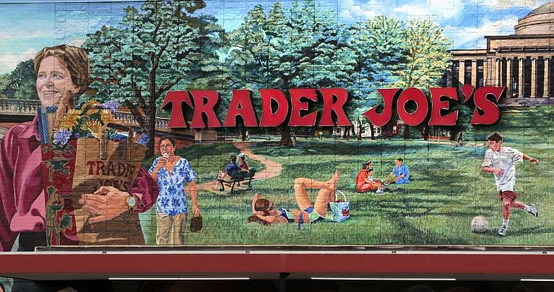 FILE - The Trader Joe's logo hangs on a mural, Aug. 13, 2019, in Cambridge, Mass. Trader Joe's recently upped the price to 23 cents for a single banana, marking a 4-cent increase from the grocer's previous going rate for the fruit that remained unchanged for over 20 years. (AP Photo/Charles Krupa, File)