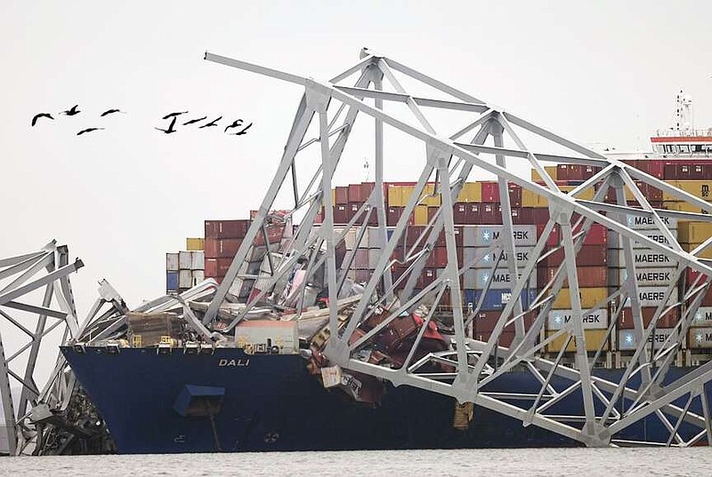 A cargo ship is stuck under the part of the structure of the Francis Scott Key Bridge after the ship hit the bridge Wednesday in Baltimore, Md. (AP Photo/Steve Helber)