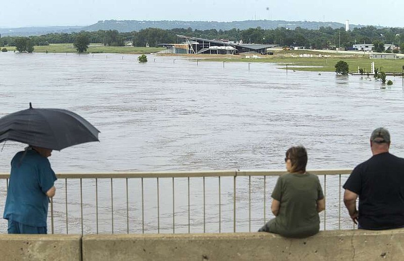 People gaze at the flooded Arkansas River Tuesday, May 28, 2019, from the bridge on Garrison Avenue in downtown Fort Smith. (NWA Democrat-Gazette/BEN GOFF)