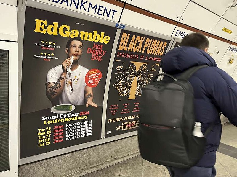 A  view of a poster advertising comedian Ed Gamble's Hot Diggity Dog tour on the Bakerloo line platform at Embankment underground station in London, Wednesday March 27, 2024. Gamble has been ordered to change a subway station poster campaign for his new standup show because the image of a hot dog violated the transit network's ban on junk food advertising. The poster for the show, “Hot Diggity Dog,” showed a mustard- and ketchup-smeared Gamble beside a half-eaten hot dog on a plate. A bemused Gamble replaced the wiener with a cucumber, and the poster was approved. (Joe Sene/PA via AP)