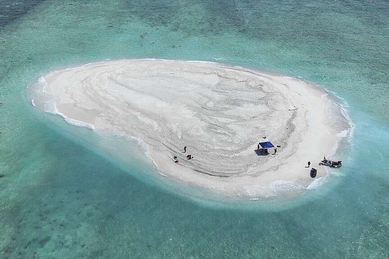 In this photo provided by the Philippine Coast Guard, Filipino scientists reach sandbars called Sandy Cay at the disputed South China Sea on Thursday March 21, 2024. Chinese coast guard ships, backed by a military helicopter, tried to dangerously block but failed to stop two Philippine government vessels carrying scientists from reaching two barren sandbars called Sandy Cay in the disputed South China Sea, Philippine officials said Friday. (Philippine Coast Guard via AP)