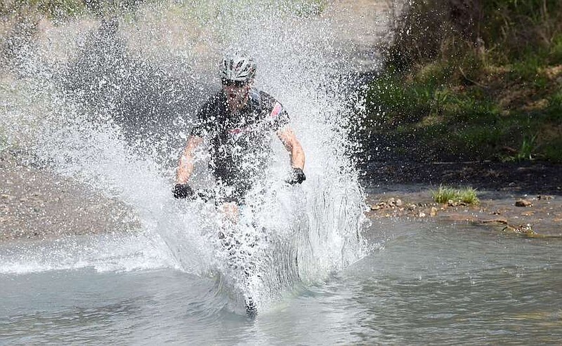 Riders in the Big Splash Contest pedal at high speeds into Lee Creek during the annual Ozark Mountain Bike Festival in 2017 at Devil's Den State Park.
(NWA Democrat-Gazette/Flip Putthoff)