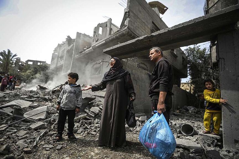 Palestinians collect their belongings from the rubble of a residential building for the Moussa family after an Israeli airstrike in the Maghazi refugee camp, central Gaza Strip, Friday, March 29, 2024. (AP Photo/Ismael Abu Dayyah)