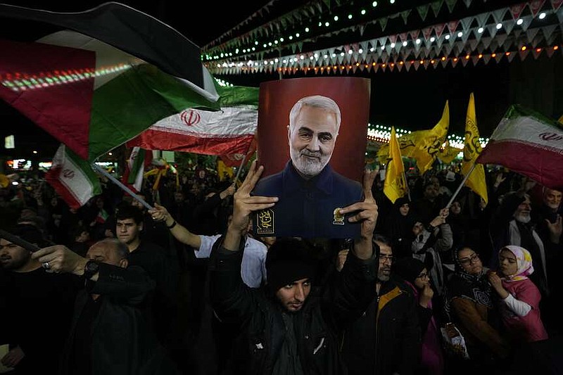 Iranian protesters wave Iranian and Palestinian flags as one of them holds up a poster of the late Iranian Revolutionary Guard Gen. Qassem Soleimani, who was killed in a U.S. drone attack in 2020, during their anti-Israeli gathering to condemn killing members of the Iranian Revolutionary Guards in Syria, at the Felestin (Palestine) Sq. in downtown Tehran, Iran, Monday, April 1, 2024. An Israeli airstrike that demolished Iran's consulate in Syria killed two Iranian generals and five officers, Syrian and Iranian officials said Monday. (AP Photo/Vahid Salemi)