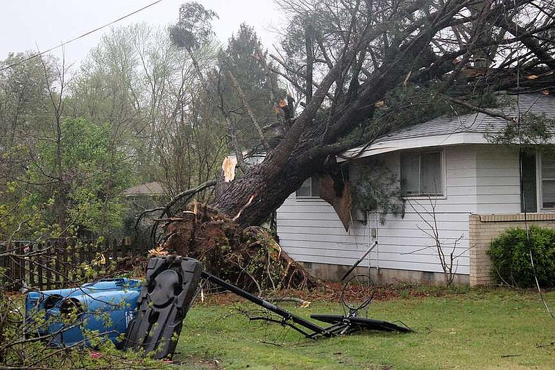 A tree rests on a house Tuesday morning in Pea Ridge after storms hit the area earlier that morning. The National Weather Service has confirmed the Tuesday morning storms spawned two tornadoes in Garfield.
(NWA Democrat-Gazette/Annette Beard)
