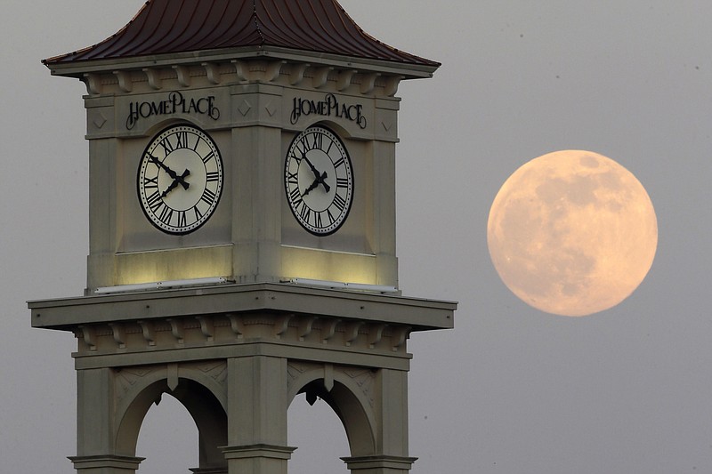 FILE - The moon rises behind the Home Place clock tower in Prattville, Ala., Saturday, June 22, 2013. NASA wants to come up with an out-of-this-world way to keep track of time, putting the moon on its own souped-up clock.  The White House on Tuesday, April 2, 2204, told NASA to work with other agencies abroad to come up with a new moon-centric time reference system.   (AP Photo/Dave Martin, File)